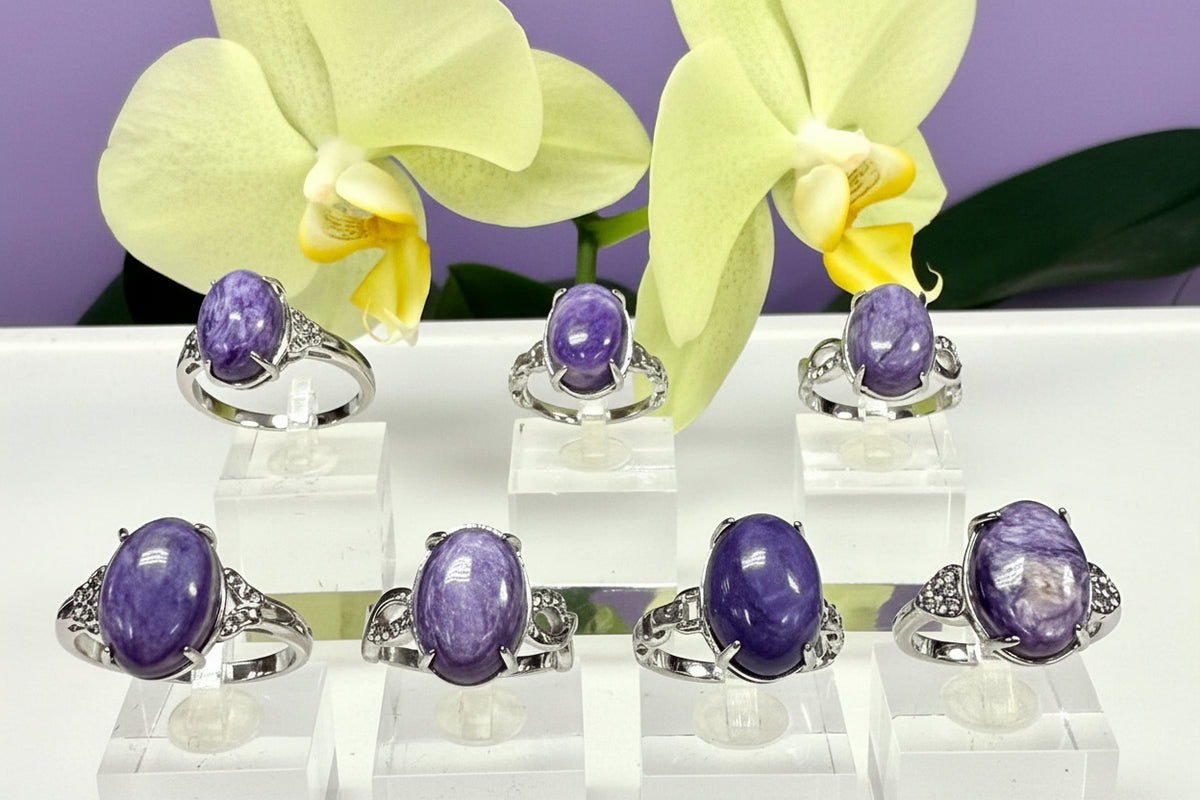 Set of purple gemstone rings on clear stands with yellow flowers in the background