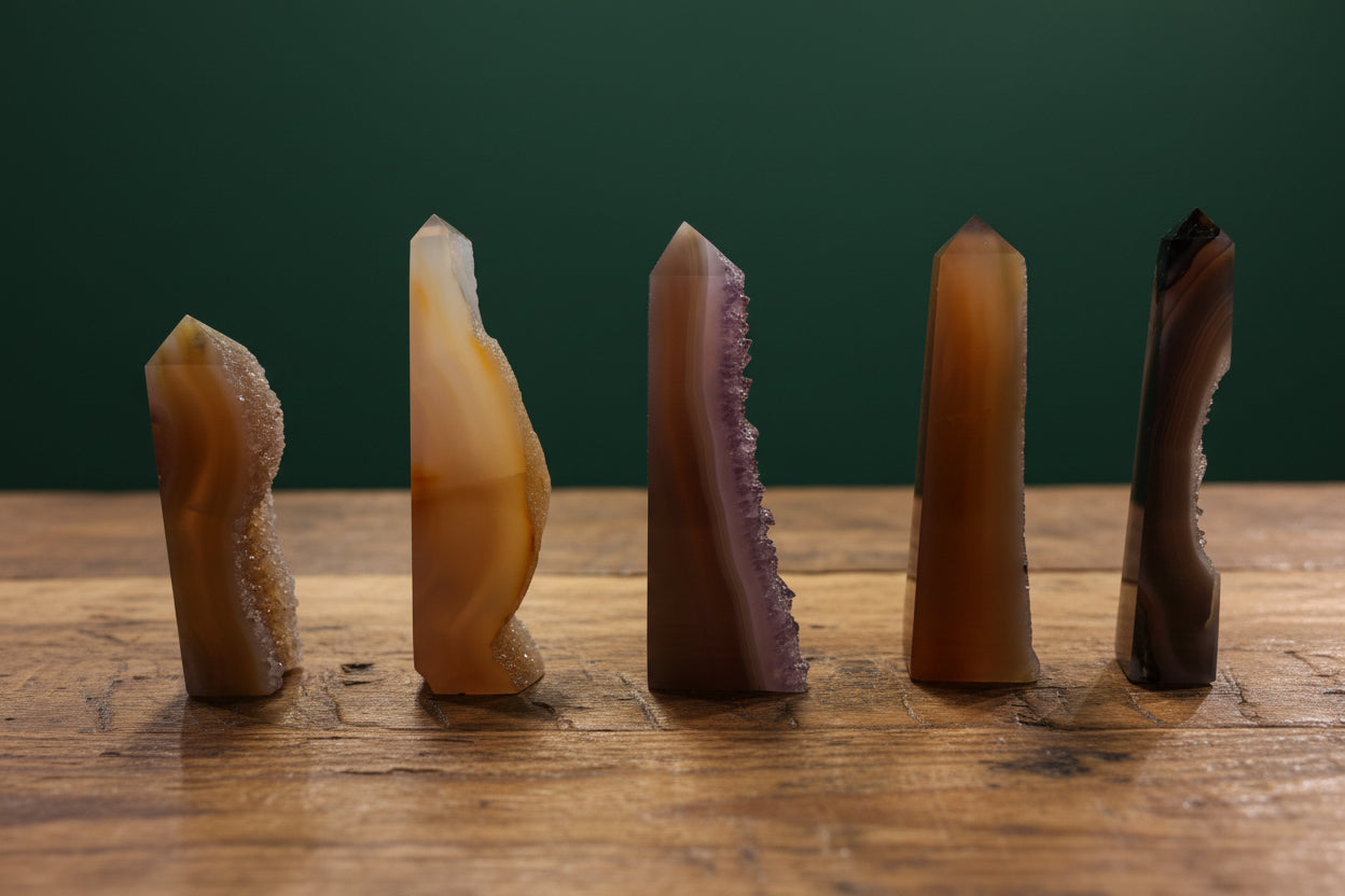 Five crystal formations on a wooden surface with a green background